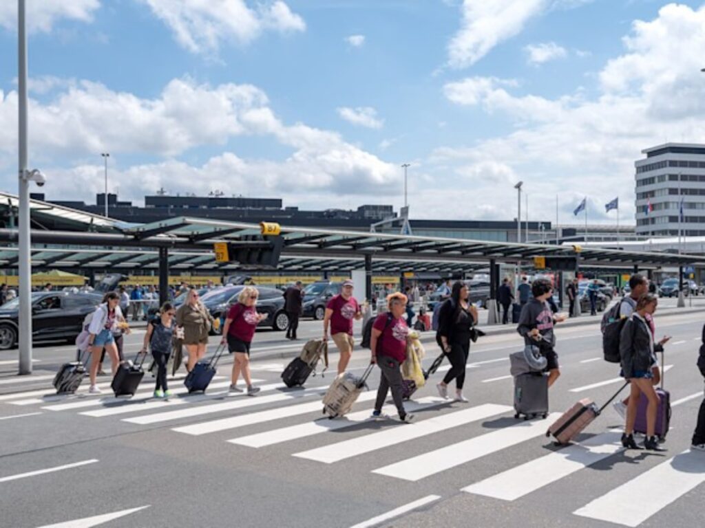 Amsterdam Airport Train vs Taxi: Which Is Better in 2026? 18 Passengers waiting at the bus terminal outside Schiphol Plaza