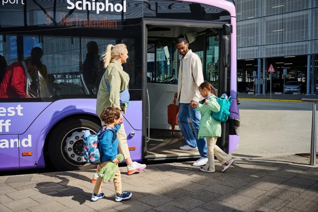 Amsterdam Airport Train vs Taxi: Which Is Better in 2026? 17 Family boarding a bus outside Schiphol Airport