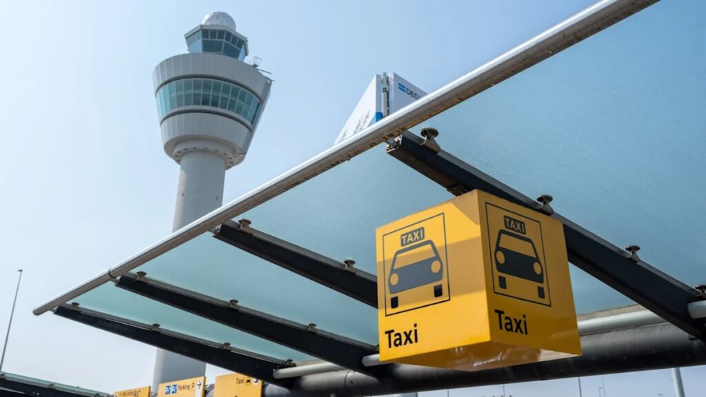 Amsterdam Airport Train vs Taxi: Which Is Better in 2026? 12 Official taxi stand sign outside Schiphol Plaza