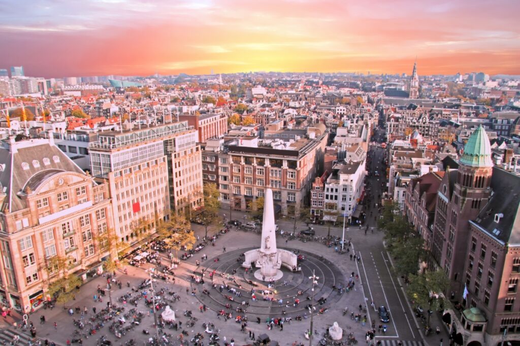 Amsterdam Airport Train vs Taxi: Which Is Better in 2026? 19 Aerial view of Dam Square and central Amsterdam at sunset