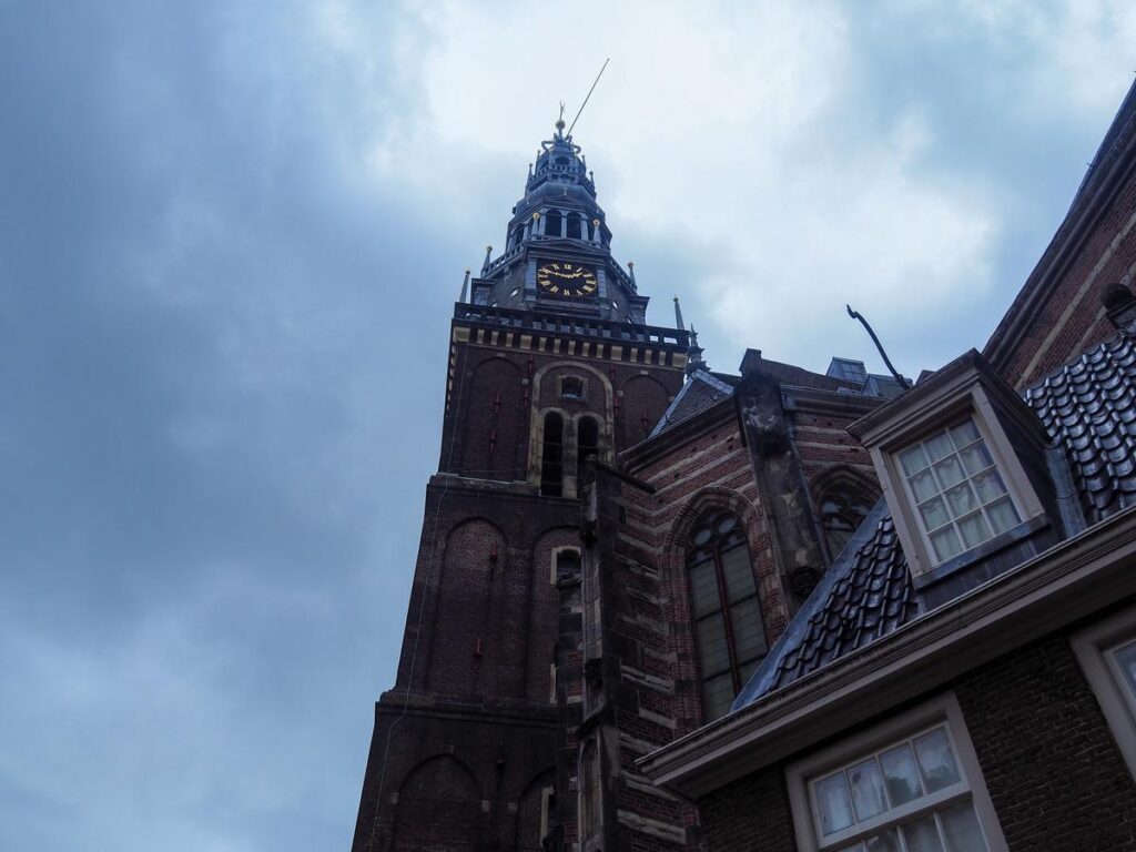 Oude Kerk tower with clock over Dutch roofs, Amsterdam