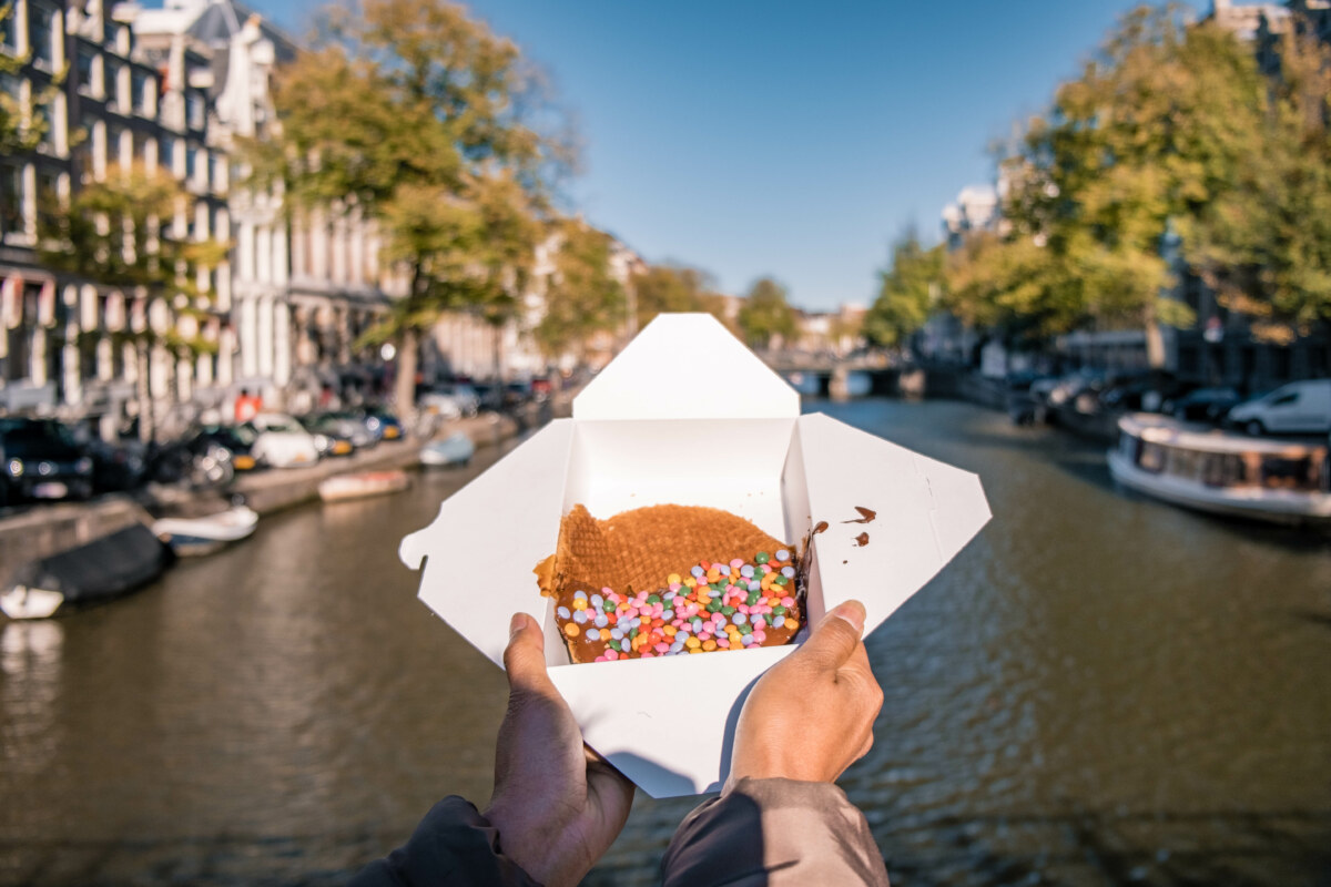 20 Insider Secrets for Exploring Amsterdam on a Shoestring: Your Ultimate Budget-Friendly Guide 6 Hands holding a Stroopwafel with caramel-like syrup in Amsterdam, Netherlands