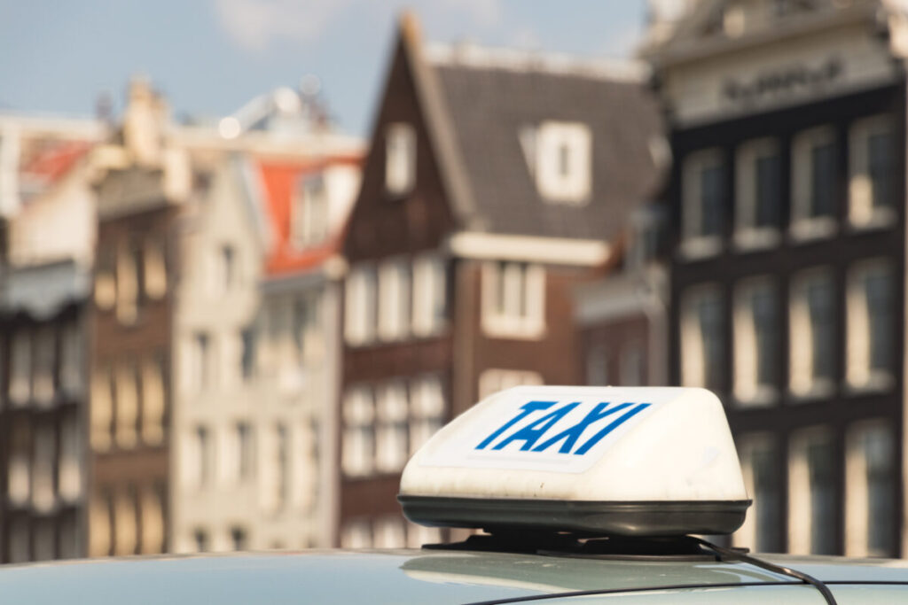 Amsterdam Airport Train vs Taxi: Which Is Better in 2026? 11 Amsterdam taxi with a blue roof sign