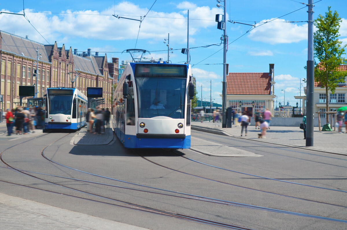 Navigate Amsterdam Like a Pro: 6 Transport Blunders to Avoid 1 Modern trams and people at tram stop on sunny day in Amsterdam