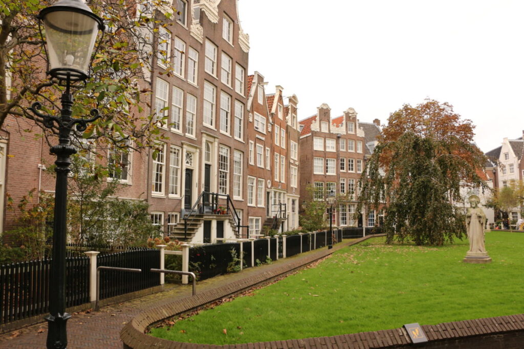 10 Pin‑Drop Perfect Places for Fall Colors in Amsterdam (Exact Spots, Zero Guesswork) 6 Begijnhof, Amsterdam featuring black lamp post stands on the left, beside a lush green park with a statue autumn foliage