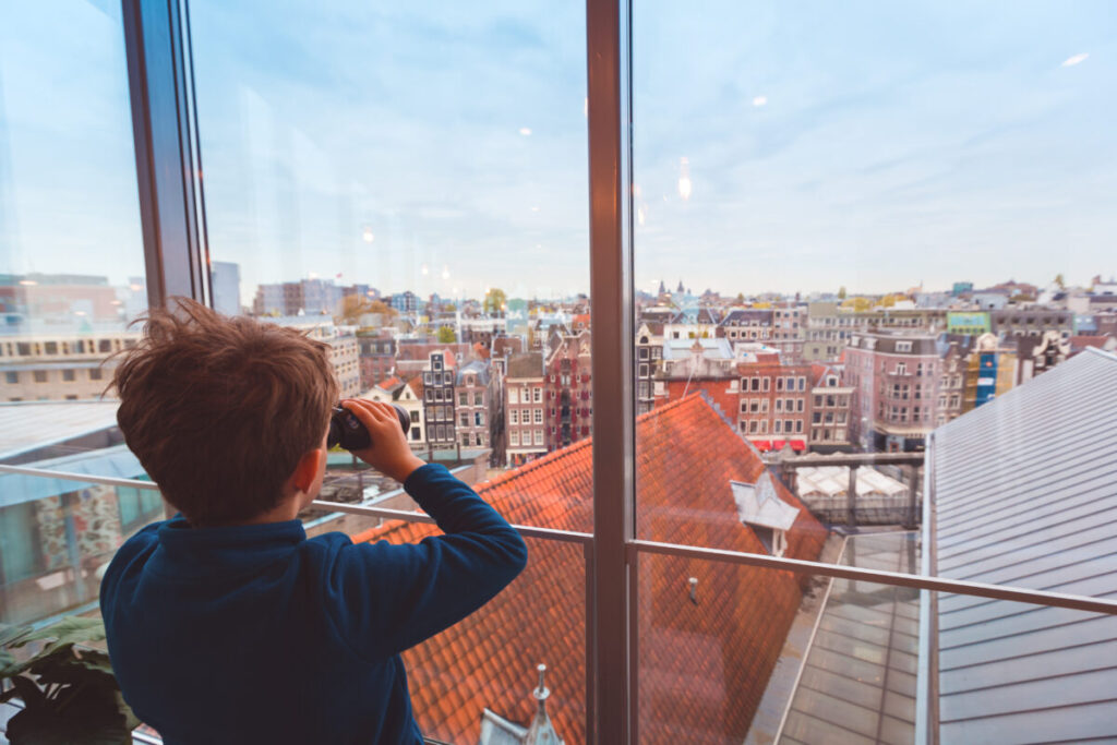 Amsterdam's Secret Wildlife: 12 Mind-Blowing Animal Encounters Hiding in Plain Sight 14 Child with binoculars gazes at Amsterdam rooftops and buildings while wildlife spotting