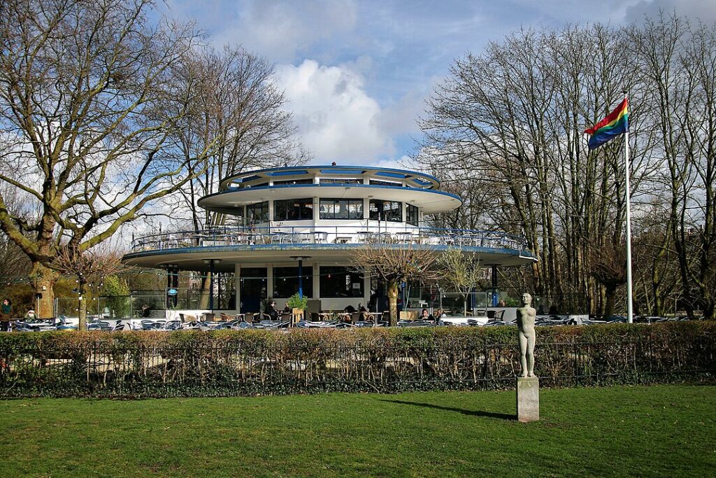 10 Pin‑Drop Perfect Places for Fall Colors in Amsterdam (Exact Spots, Zero Guesswork) 8 Large circular building, Blauwe Theehuis in Amsterdam, surrounded by vibrant autumn foliage.