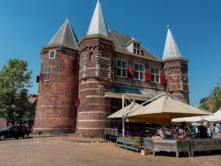 Historic De Waag building and café terrace on Nieuwmarkt square on a sunny afternoon in Amsterdam