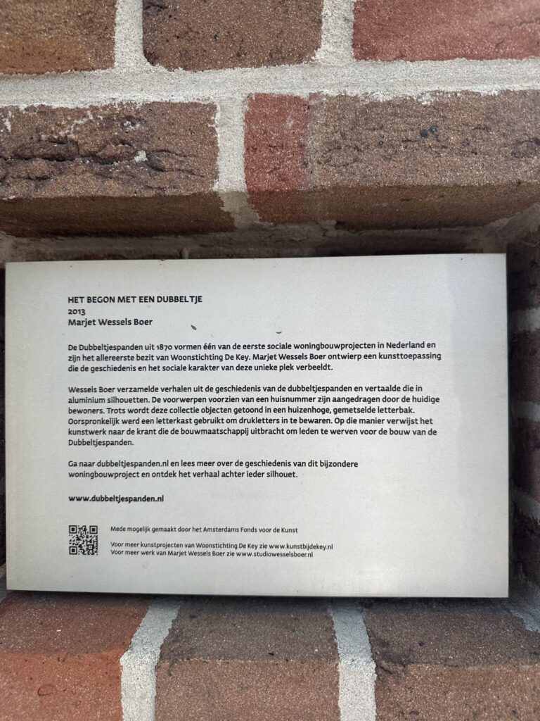 Dubbeltjespanden 5 Informational plaque on the Dubbeltjespanden brick wall explaining the artwork Het begon met een dubbeltje by Marjet Wessels Boer