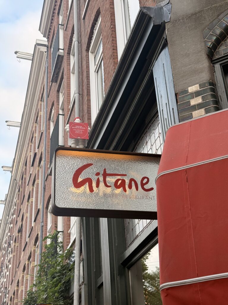 Gitane café and restaurant illuminated storefront sign at dusk in Amsterdam Oud-West
