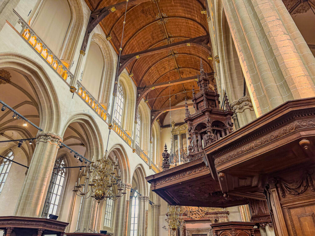 The New Church (De Nieuwe Kerk) 5 Gothic church interior with vaulted ceiling, stone arches, ornate pulpit, and chandeliers.
