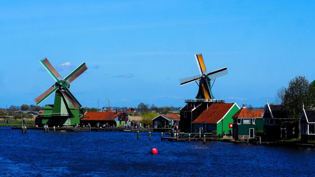Kinderdijk vs Zaanse Schans Windmills: Which Dutch Icon Wins? 3 The historic windmills of Zaanse Schans, set along the river, with traditional Dutch houses