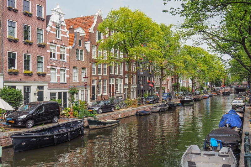How to Visit Amsterdam on a Tight Budget (2026) 4 Canal houses beside the water in Amsterdam's Jordaan neighborhood