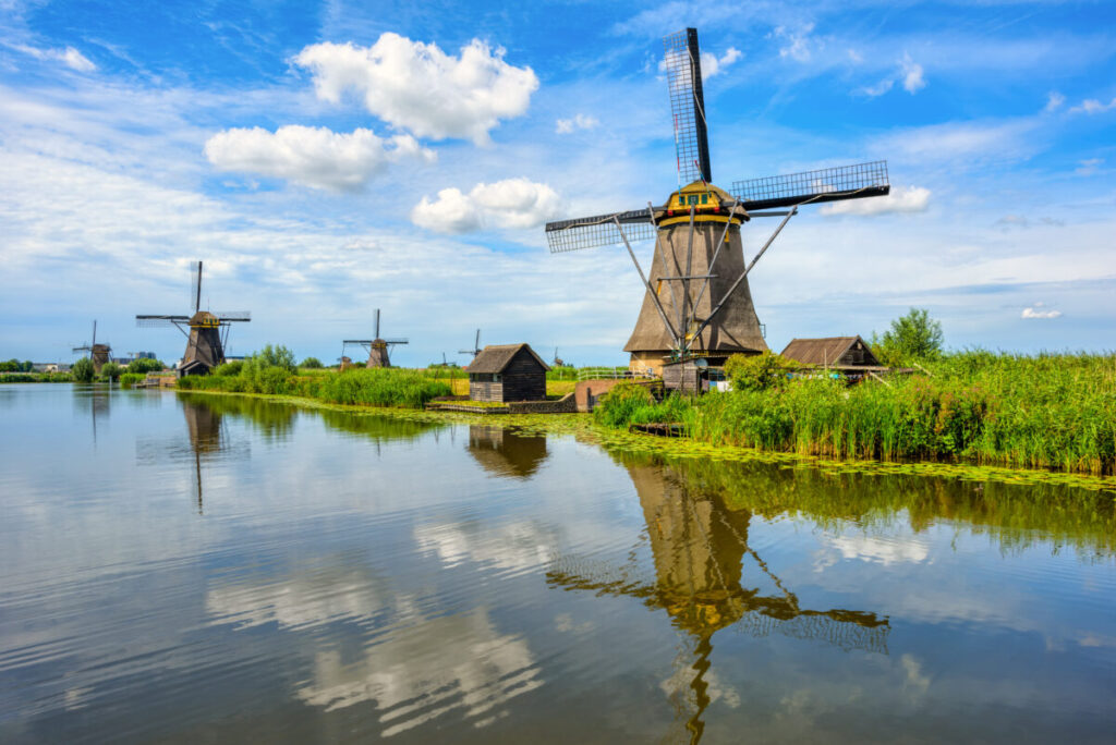 Kinderdijk vs Zaanse Schans Windmills: Which Dutch Icon Wins? 8 Scenic view of traditional windmills at Kinderdijk, Holland, surrounded by lush greenery and calm waterways.