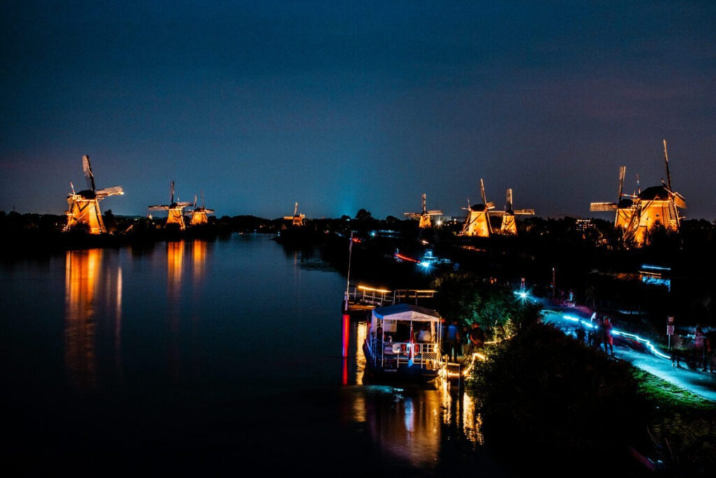 Kinderdijk vs Zaanse Schans Windmills: Which Dutch Icon Wins? 23 Kinderdijk nighttime view of a river with glowing windmills, celebrating Kinderdijk Illumination Week.