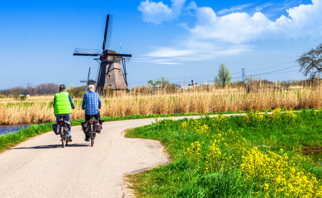 Kinderdijk vs Zaanse Schans Windmills: Which Dutch Icon Wins? 19 Scenic view of Kinderdijk windmills as a couple enjoys a bike ride through the picturesque Holland countryside.