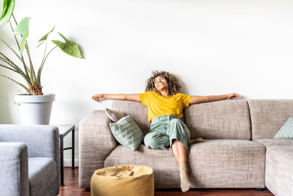 How to Create 'Gezellig' in Your Home, Inspired by Amsterdam 7 Woman happily relaxing on a sofa at a cozy living room