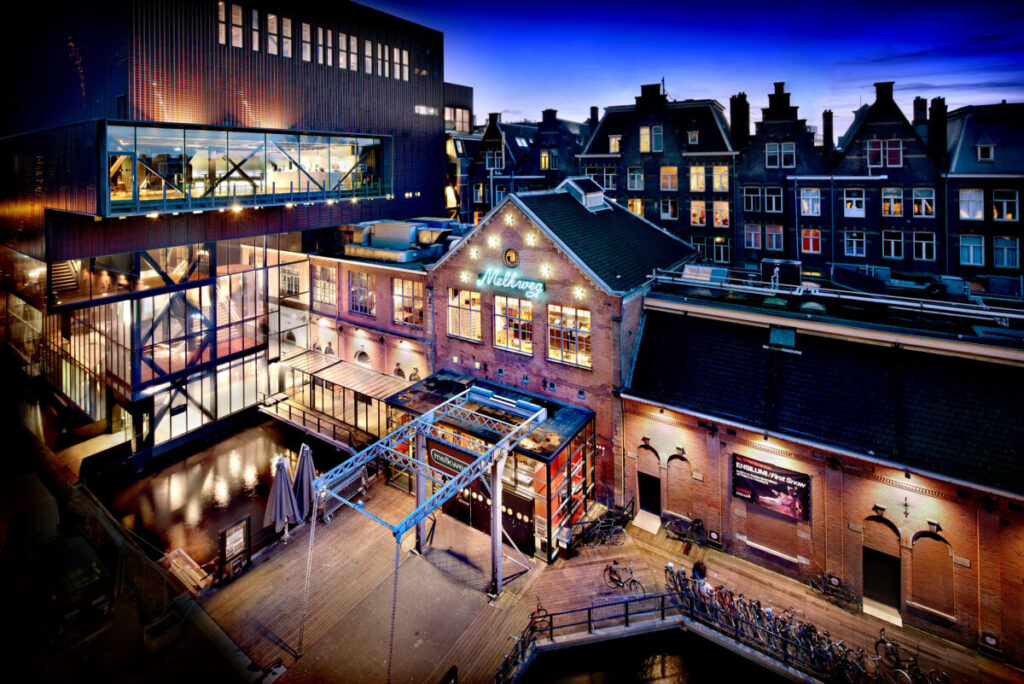 Where to Stay for Amsterdam Dance Event: 2026’s Top Areas & Insider Tips 14 Night view of Melkweg in Amsterdam, featuring a prominent building and a clock tower illuminated against the dark sky.