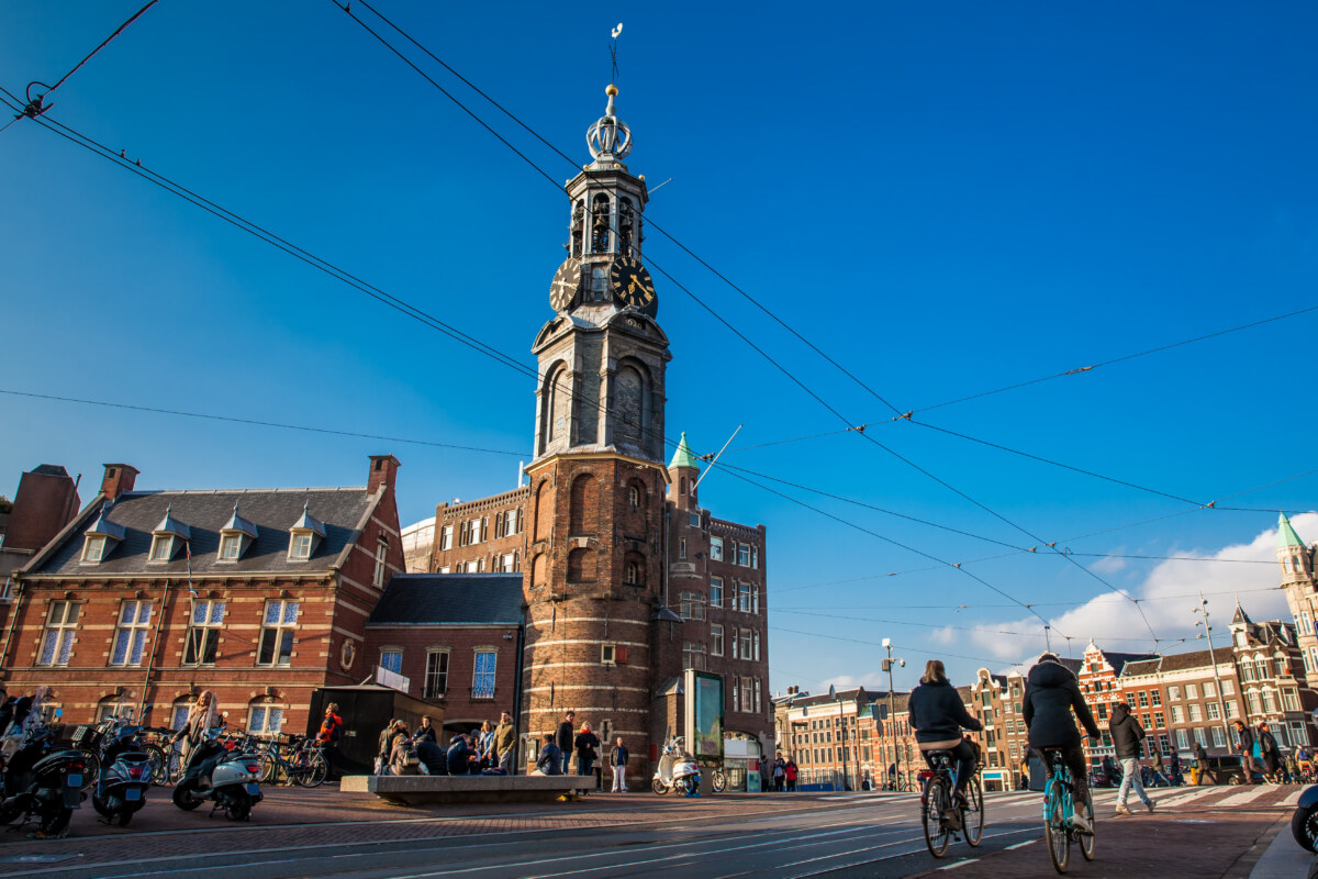 The Evolution of Tourism in the Netherlands: 24 Surprising Insights 2 People walking and biking near the Mint Tower at Muntplein Square in Amsterdam, Netherlands