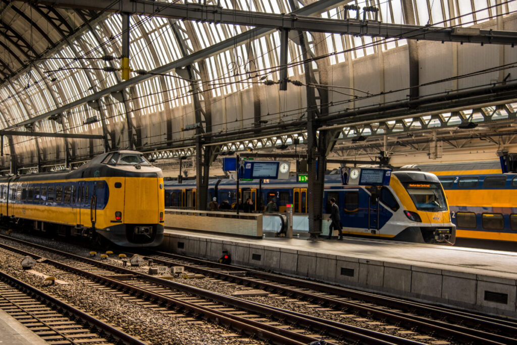 Amsterdam Airport Train vs Taxi: Which Is Better in 2026? 10 Yellow and blue NS train at Amsterdam Centraal Station