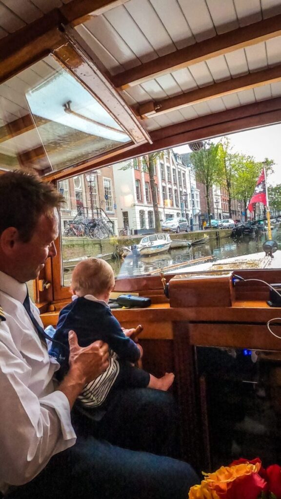 Intimate boat cabin view, Amsterdam canal, adult with child, cozy urban scene.