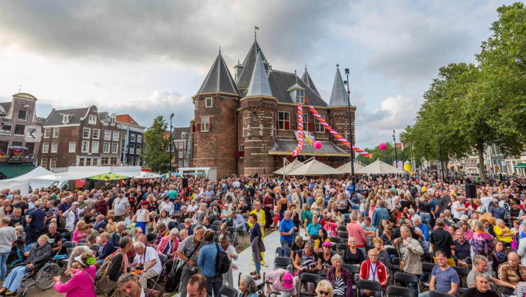 Amsterdam Pride 2026: Your Guide to the Canal Parade & Saturday Party Day 10 Diverse crowd at Pride Amsterdam, celebrating with enthusiasm, colorful outfits, and banners of support