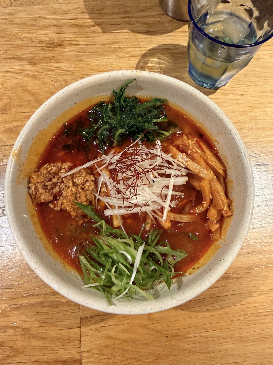 Ramen Kingdom 5 Overhead view of a spicy ramen bowl topped with scallions chili threads and menma