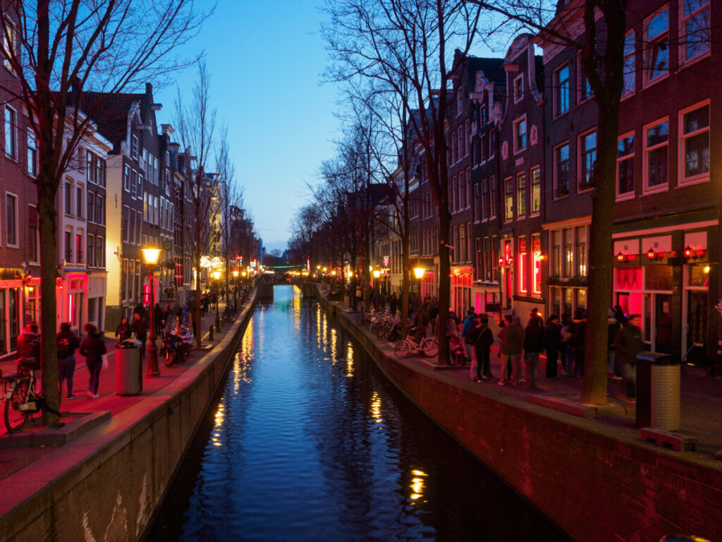 View of the canal and lights of the Red Light District at night in Amsterdam