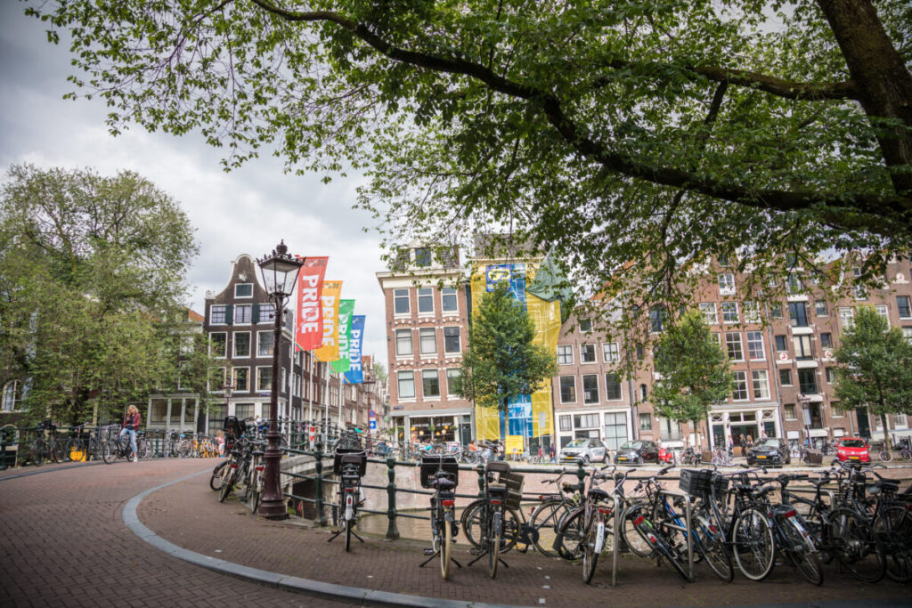 Amsterdam Pride 2026: Your Guide to the Canal Parade & Saturday Party Day 7 Bicycle parked on Reesluis bridge, surrounded by colorful Pride flags waving in the breeze.