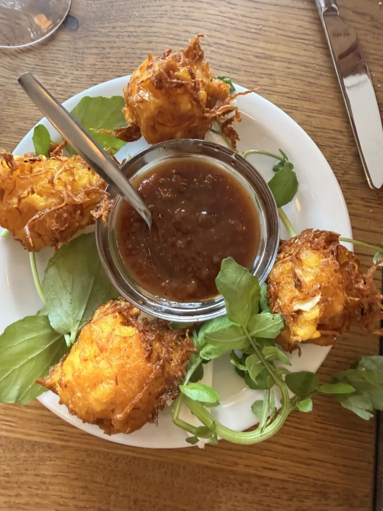 Golden-brown fried croquettes or sweetbread fritters served with watercress and a rich dipping sauce on a white plate at Restaurant Calisto.