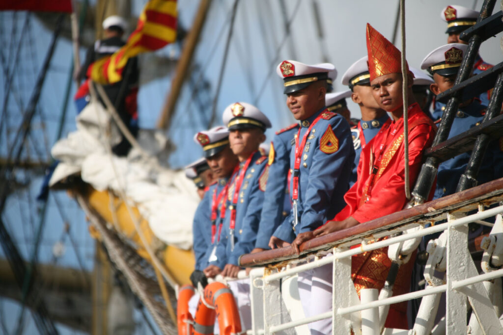 SAIL Amsterdam: 2025 Lookback and When the Next Edition Sails In (2030) 5 Naval crew members in uniforms gathered on a ship's deck, showcasing camaraderie at the SAIL Amsterdam festival.