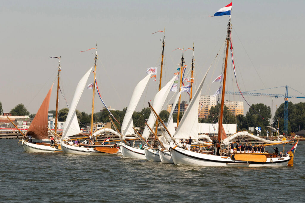 SAIL Amsterdam: 2025 Lookback and When the Next Edition Sails In (2030) 14 Colorful ships glide through Amsterdam's canals, highlighting the city's rich sailing heritage and picturesque scenery.