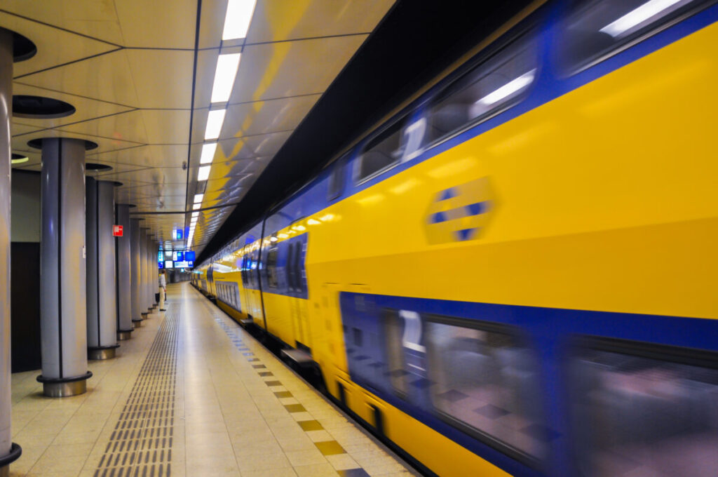 Amsterdam Airport Train vs Taxi: Which Is Better in 2026? 8 NS train passing through Schiphol Airport railway station