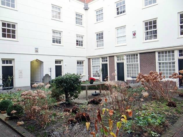 How to Find Hidden Hofjes in the Jordaan: Secret Courtyards & Local Tips 6 Peaceful courtyard in Sint Andrieshofje Amsterdam, adorned with greenery and a winding brick walkway.