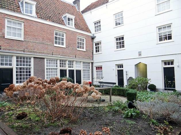 How to Find Hidden Hofjes in the Jordaan: Secret Courtyards & Local Tips 7 The tranquil Sint Andrieshofje courtyard showcases vibrant plants alongside a picturesque brick pathway.