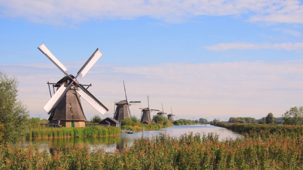 Kinderdijk vs Zaanse Schans Windmills: Which Dutch Icon Wins? 9 Scenic view of traditional windmills at Kinderdijk, Holland, surrounded by lush greenery and calm waterways.