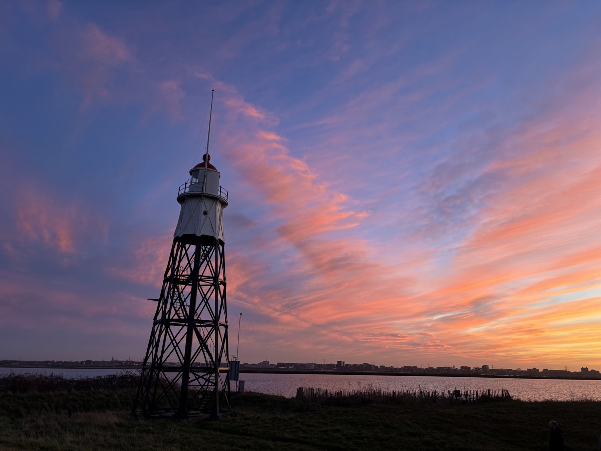 Vuurtoreneiland 7 Cast-iron lighthouse on Vuurtoreneiland silhouetted against pink and orange sunset clouds over the IJmeer