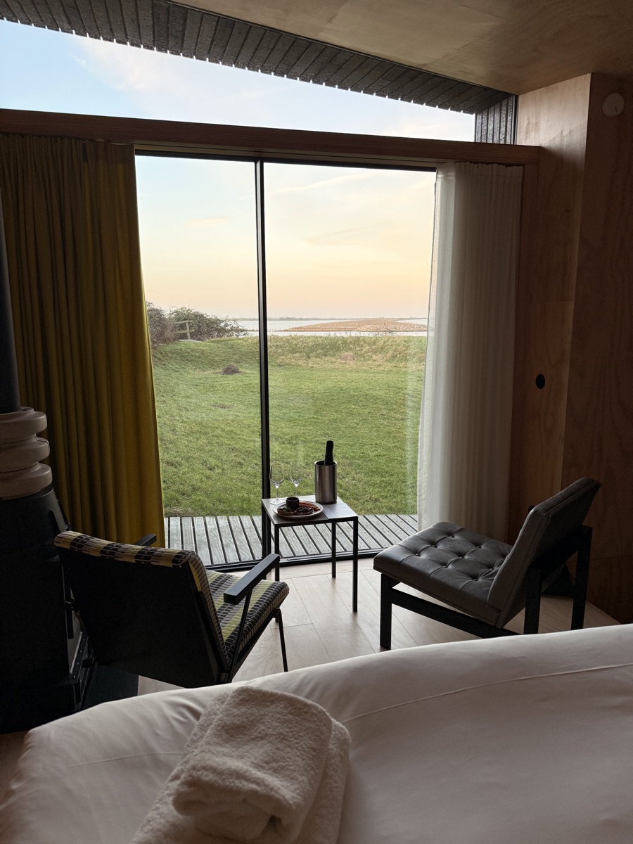Vuurtoreneiland 20 Floor-to-ceiling glass window framing grassy dunes and the calm waters of the IJmeer