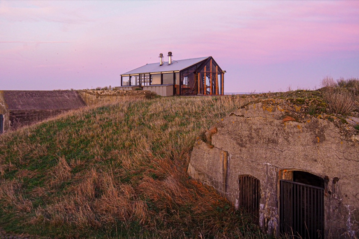 Vuurtoreneiland 5 Glasshouse restaurant perched on grassy fortifications above a concrete bunker at twilight on Vuurtoreneiland