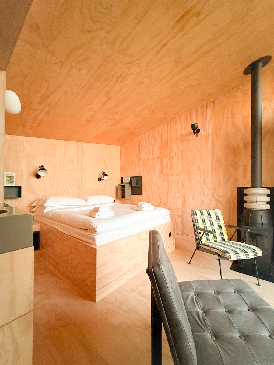 Vuurtoreneiland 18 Timber-lined cabin bedroom with double bed, crisp white linens, and modern Scandinavian seating