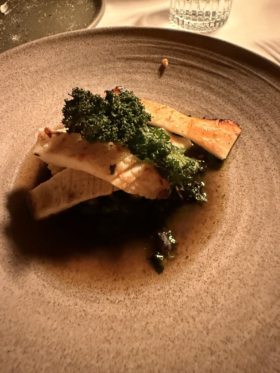 Vuurtoreneiland 13 Pan-seared fish fillet topped with flash-fried kale in a rich reduction on an earthenware plate