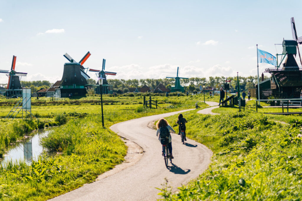 Kinderdijk vs Zaanse Schans Windmills: Which Dutch Icon Wins? 13 Scenic view of Zaanse Schans in the Netherlands, featuring traditional windmills and cyclists enjoying the picturesque landscape.